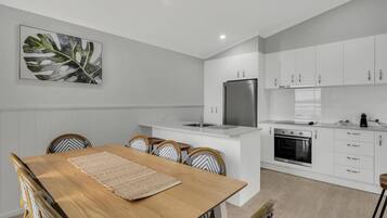 A modern kitchen with white cabinets, a built-in oven, and a stainless steel refrigerator.