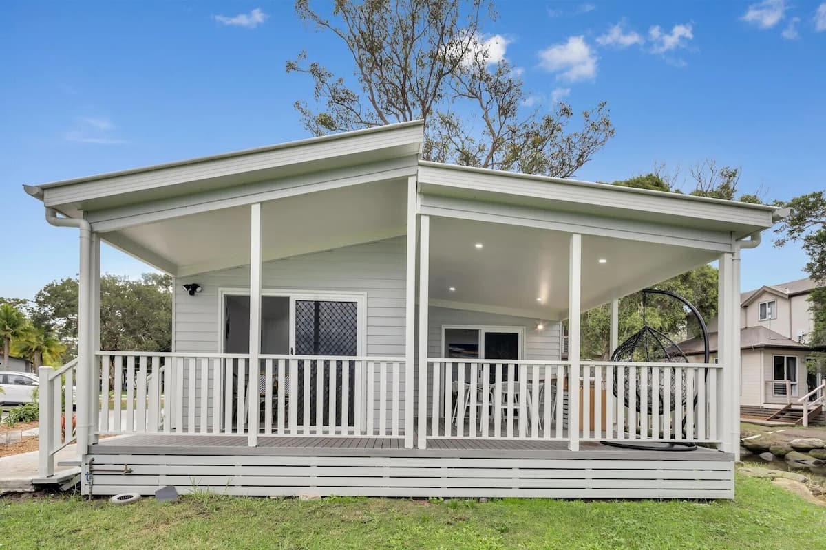 Een gelijkvloers huis met een overdekte veranda, een omheind terras en een kleine voortuin.