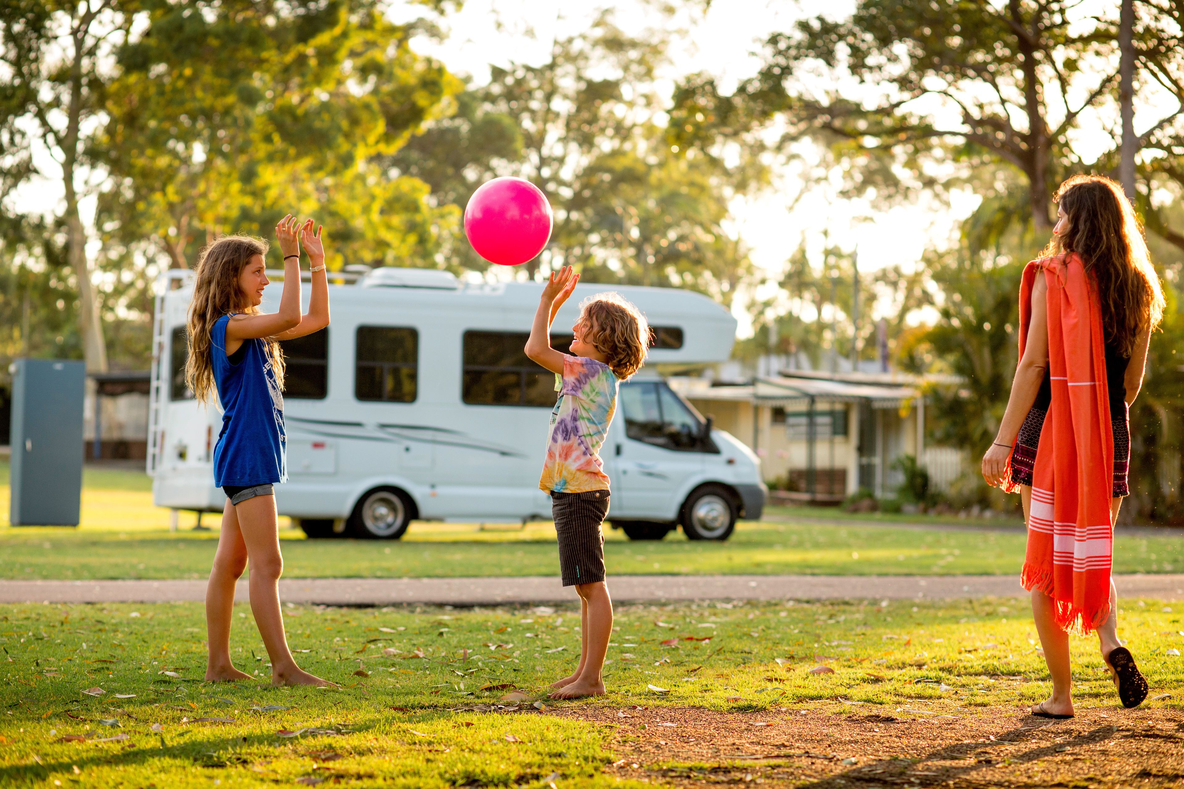 Una zona erbosa con un camper bianco sullo sfondo.