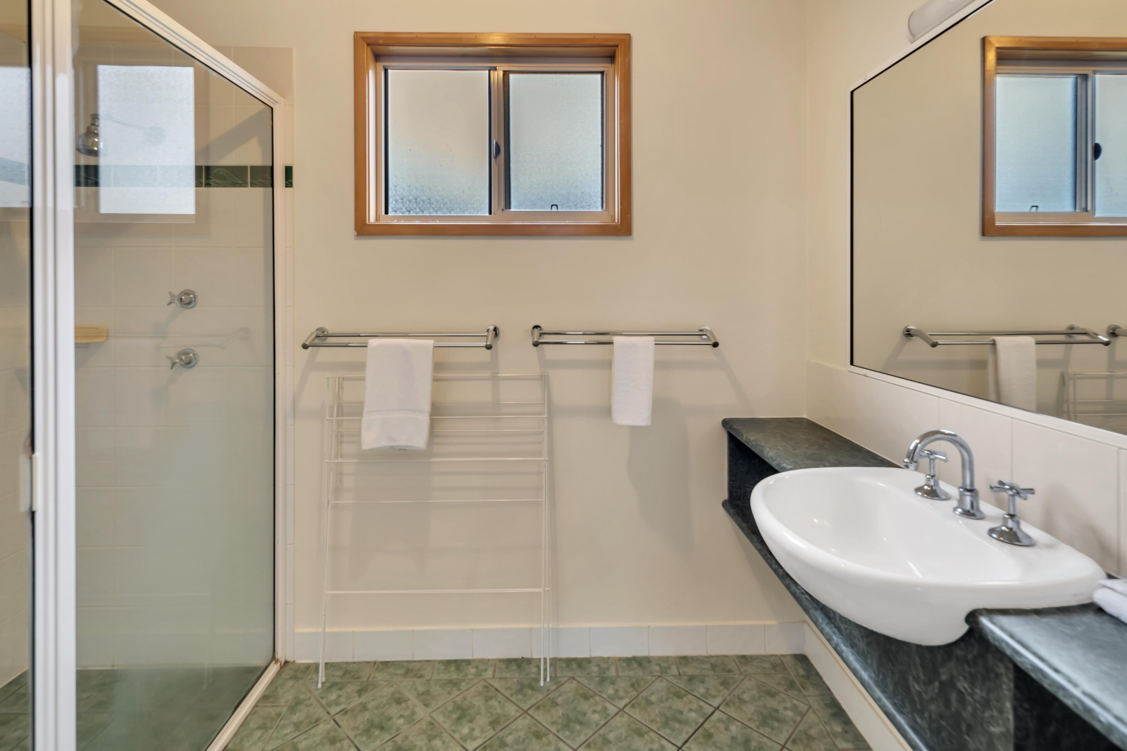 A bathroom with a glass shower enclosure, a white sink, and a mirror above the sink.
