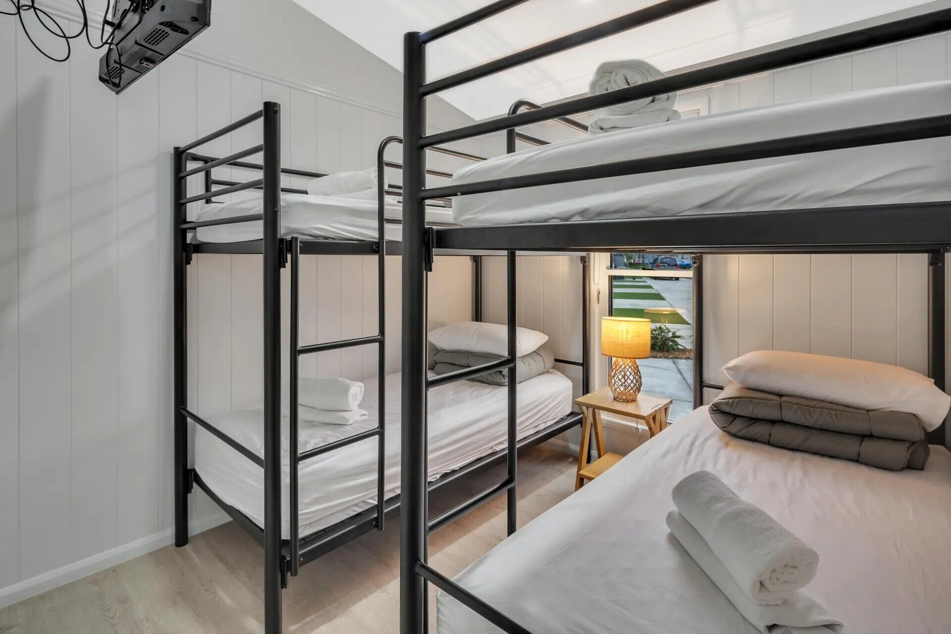 A bunk bed room with a wooden nightstand and a lamp.