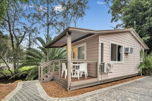 Een klein, gelijkvloers huis met een overdekte veranda en een terras.