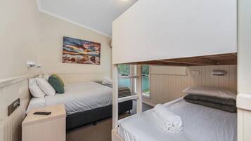 Une chambre avec deux lits, un tableau au mur et une fenêtre donnant sur un paysage.