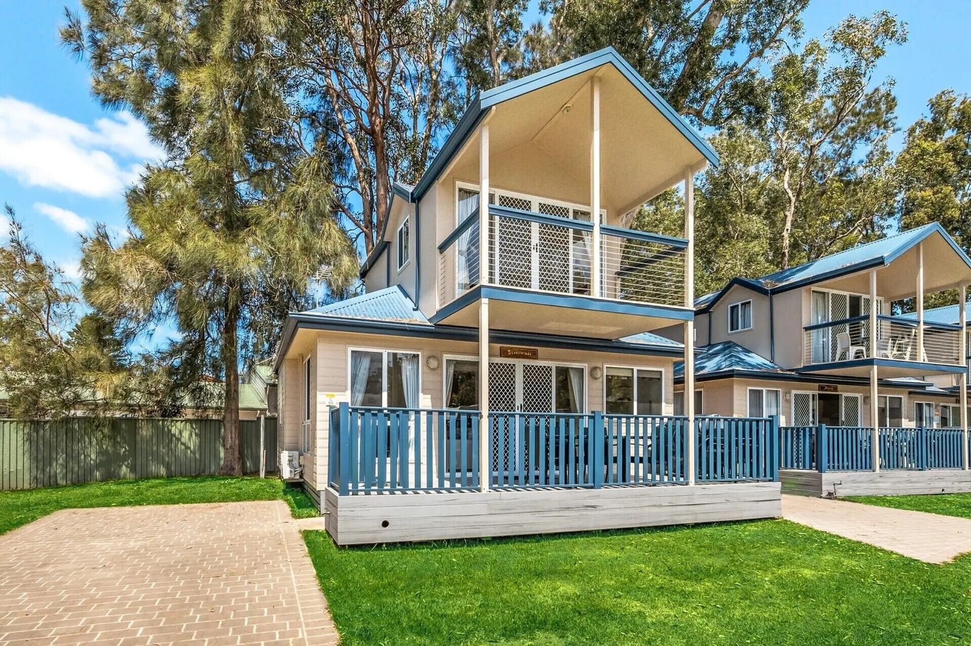 Ein zweistöckiges Haus mit einer Veranda und einem umzäunten Garten.