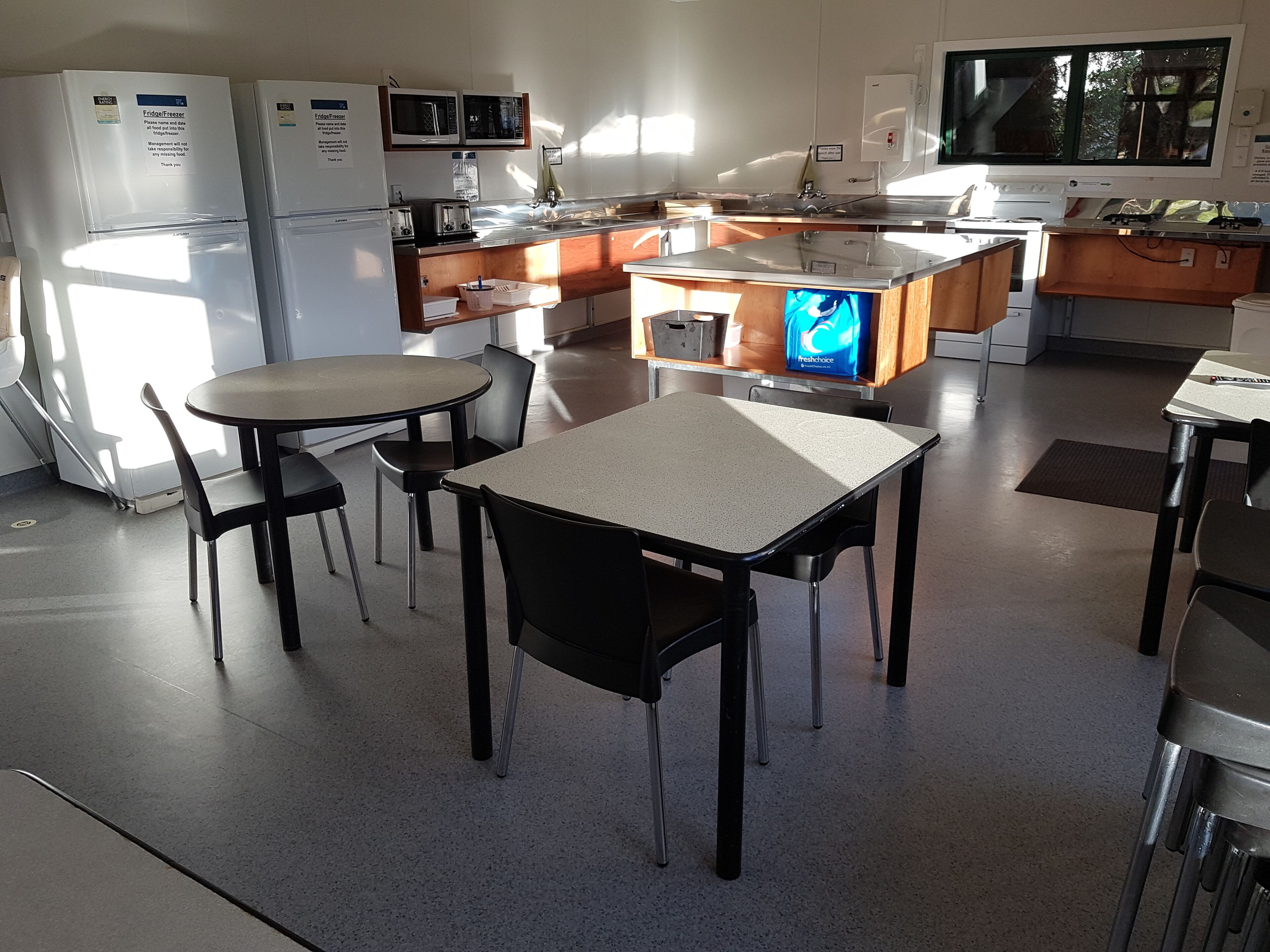 Een moderne keuken met witte apparaten, een houten aanrecht en een eetgedeelte met een tafel en stoelen.