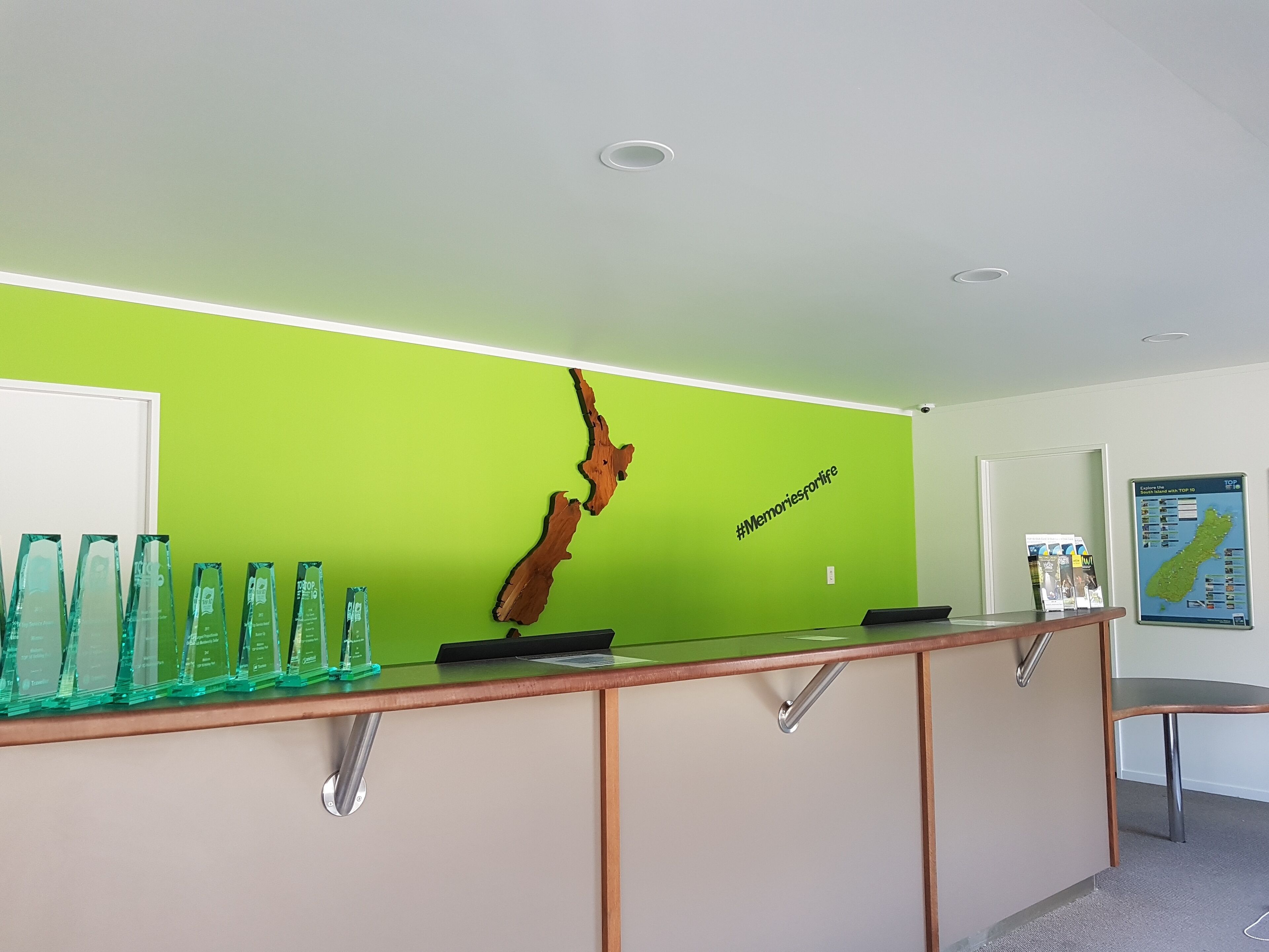 A reception desk with a green wall, wooden panels, and a wooden sculpture.
