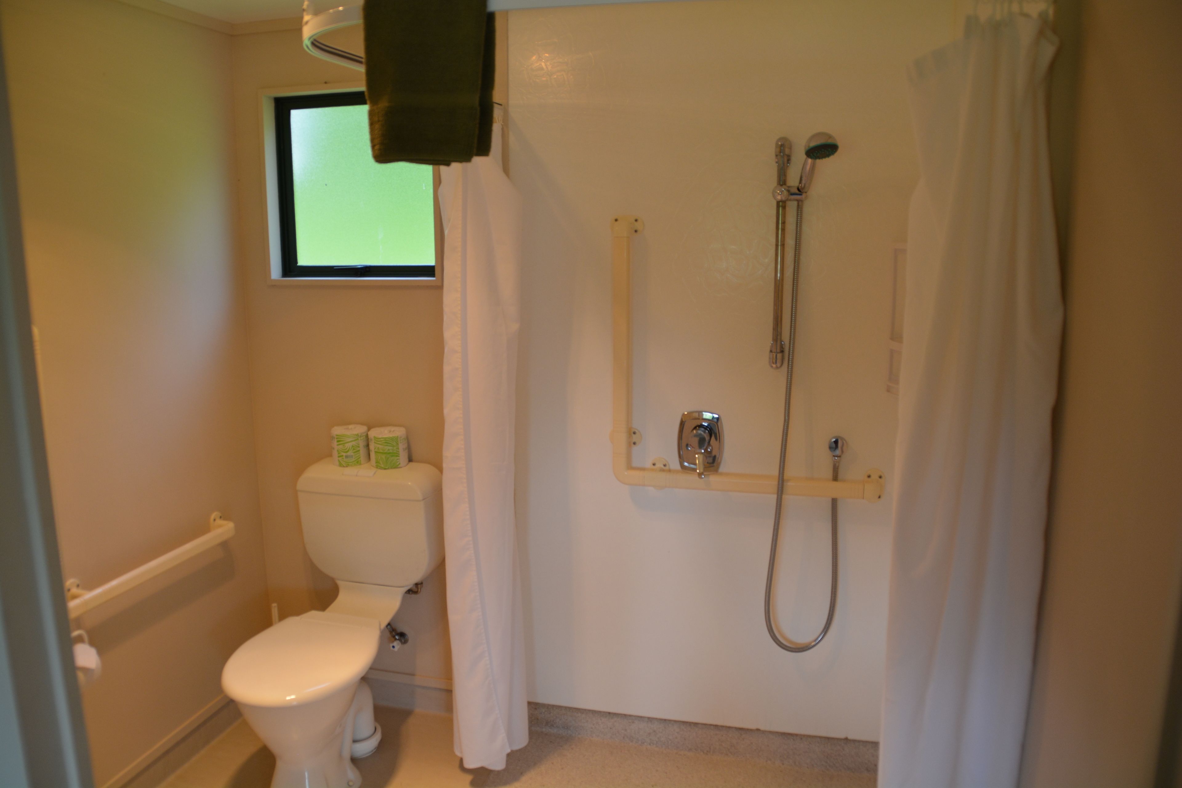 A bathroom with a toilet, a shower, and a window.
