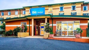 Un hôtel ibis budget avec une façade en briques, de grandes fenêtres et une enseigne bleue.
