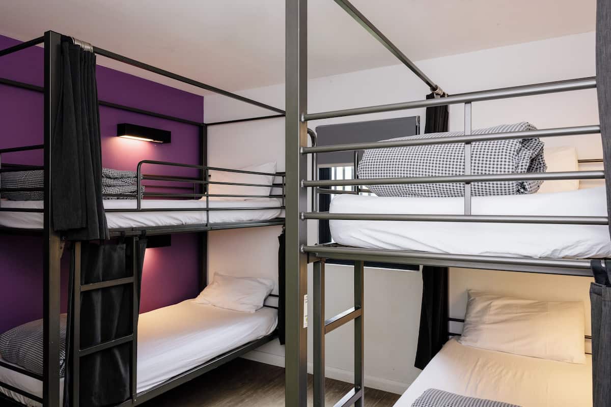 A bunk bed room with purple walls and a window.