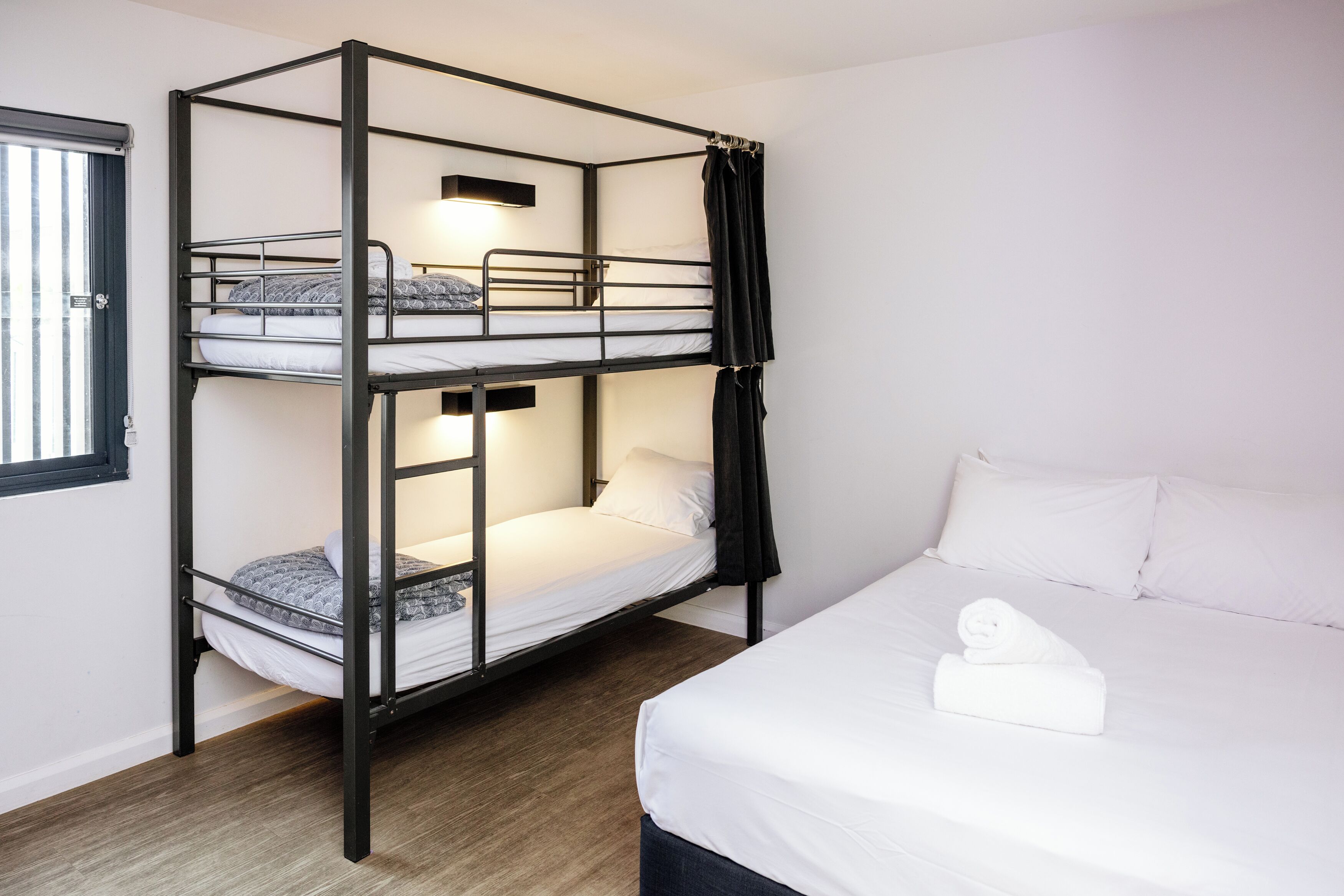 Habitación con literas, una cama individual y una toalla bien doblada en la litera inferior.