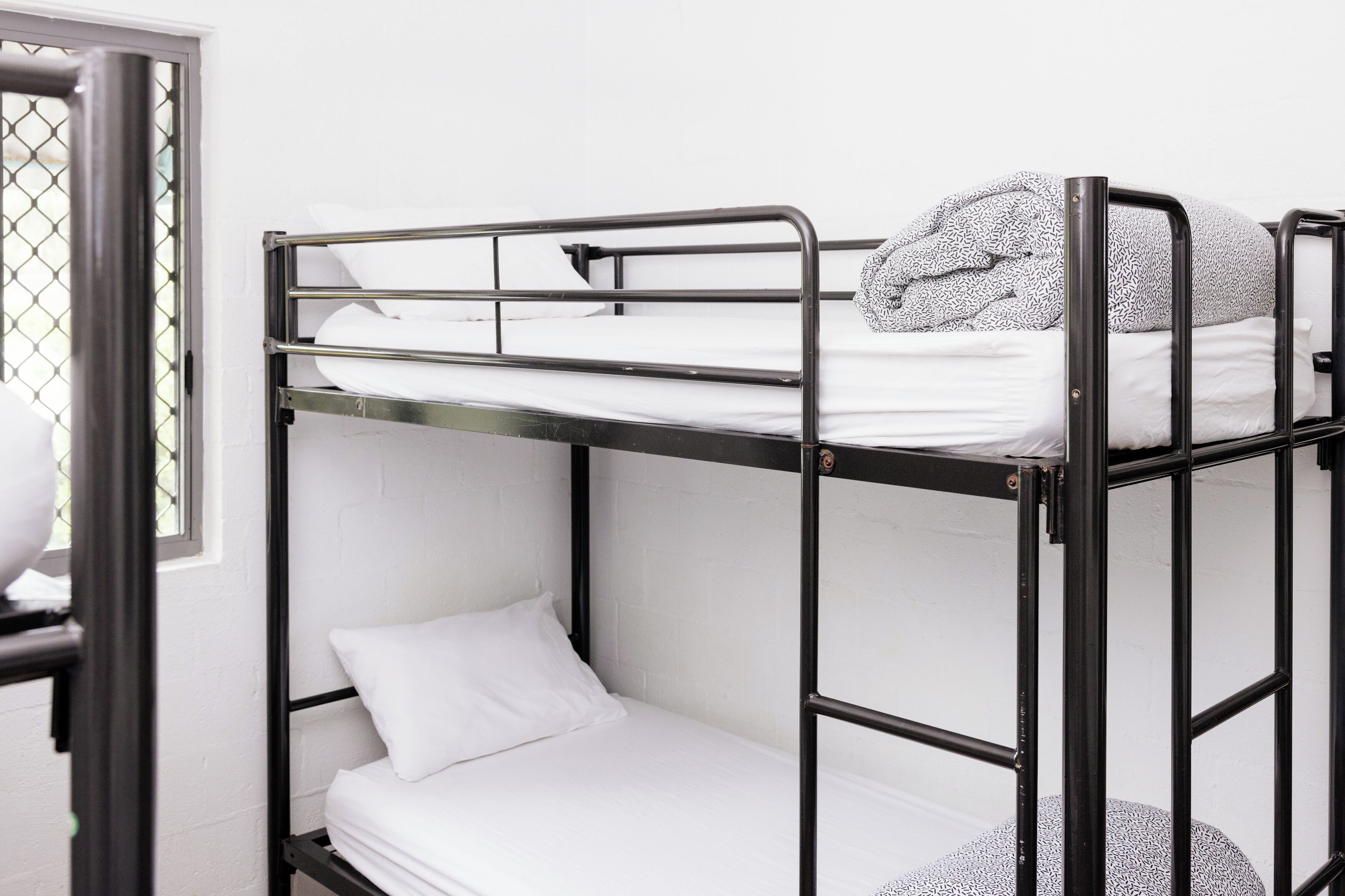 A bunk bed with white bedding and a patterned blanket on top.