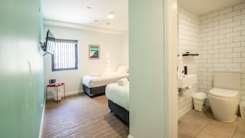 Un dormitorio con cama, mesita de noche y ventana con persianas.