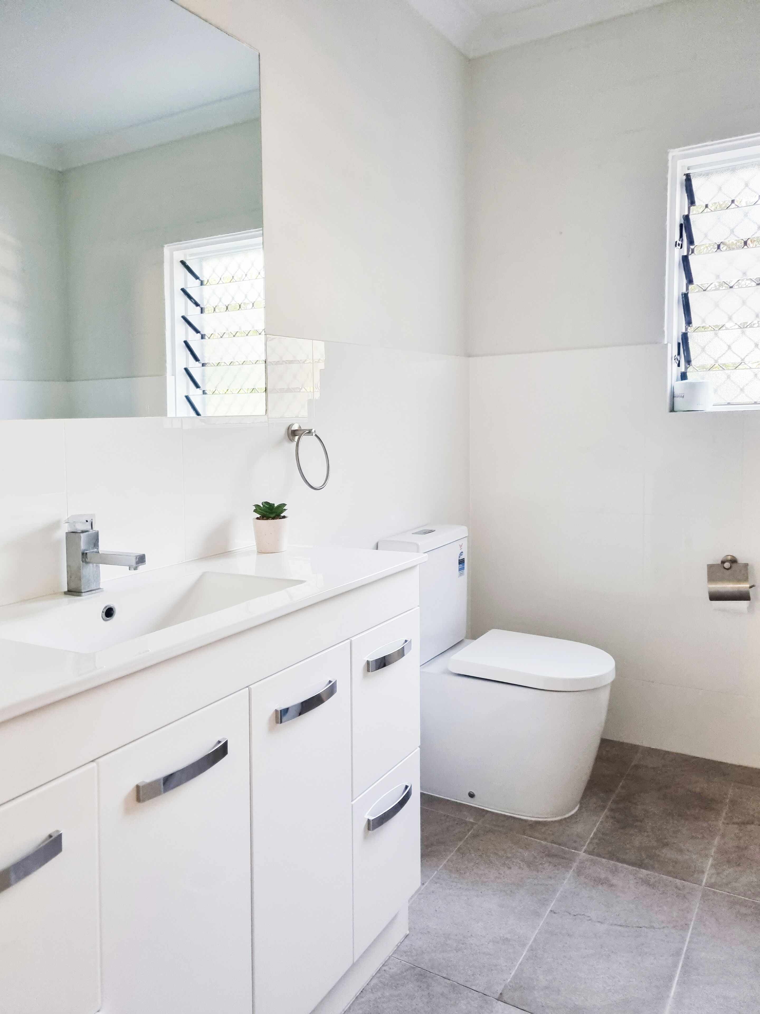 Een moderne badkamer met een wit wastafelmeubel, wastafel en toilet.