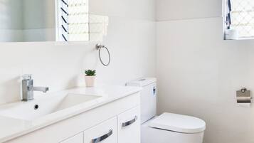 Een moderne badkamer met een wit wastafelmeubel, wastafel en toilet.