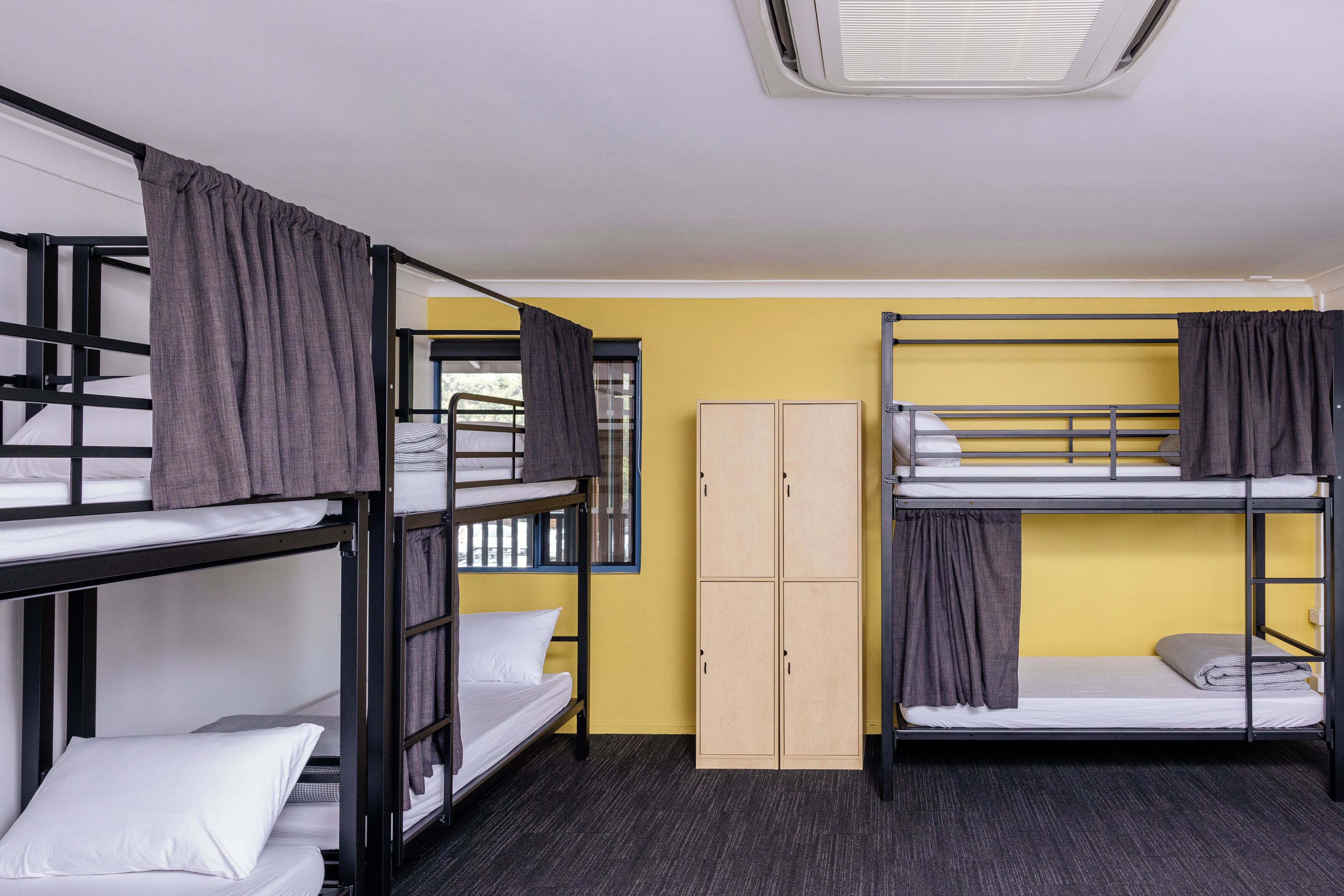 Un dormitorio con literas, un armario y una ventana con cortinas.