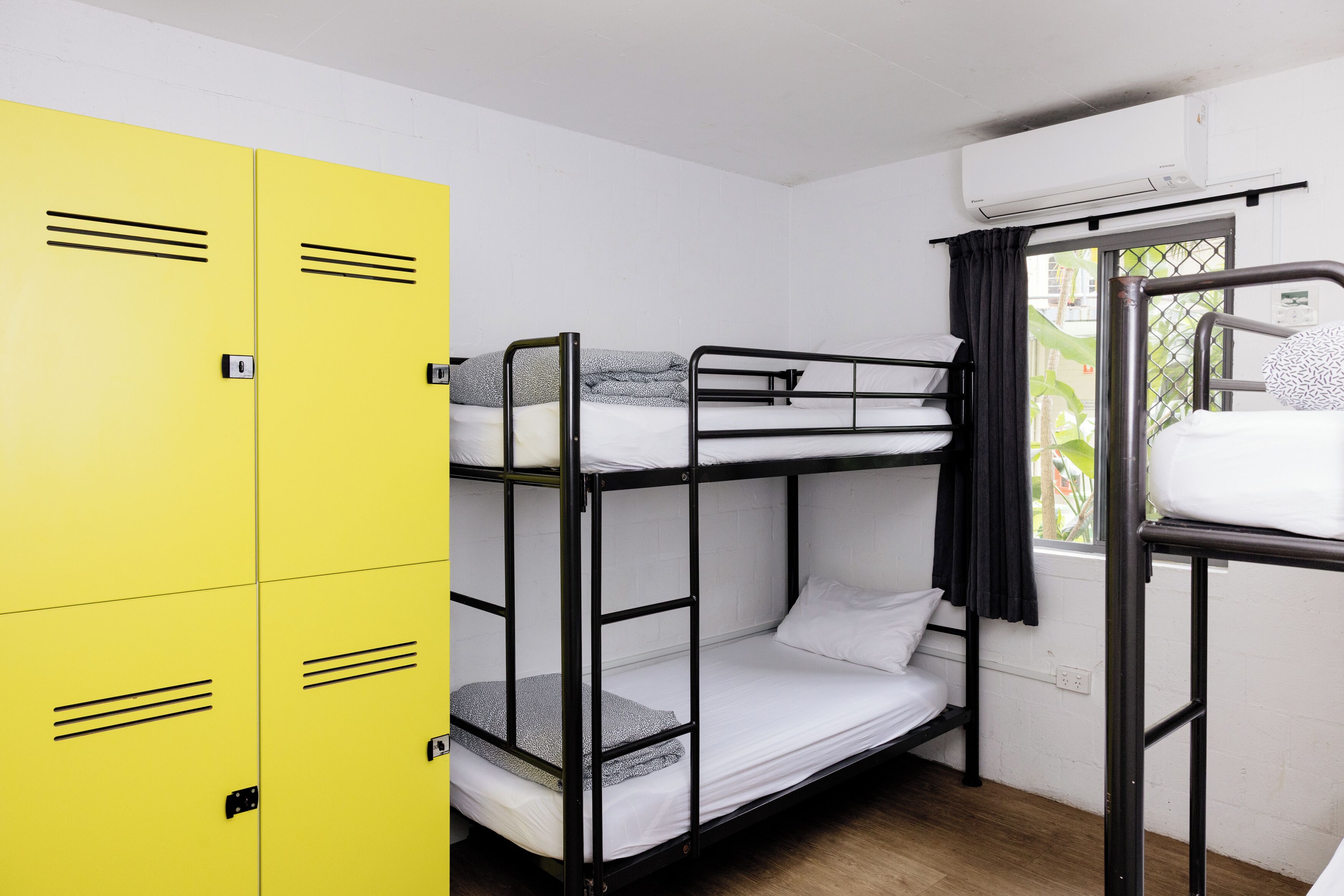 Een slaapkamer met stapelbedden, gele kasten en een raam met gordijnen.