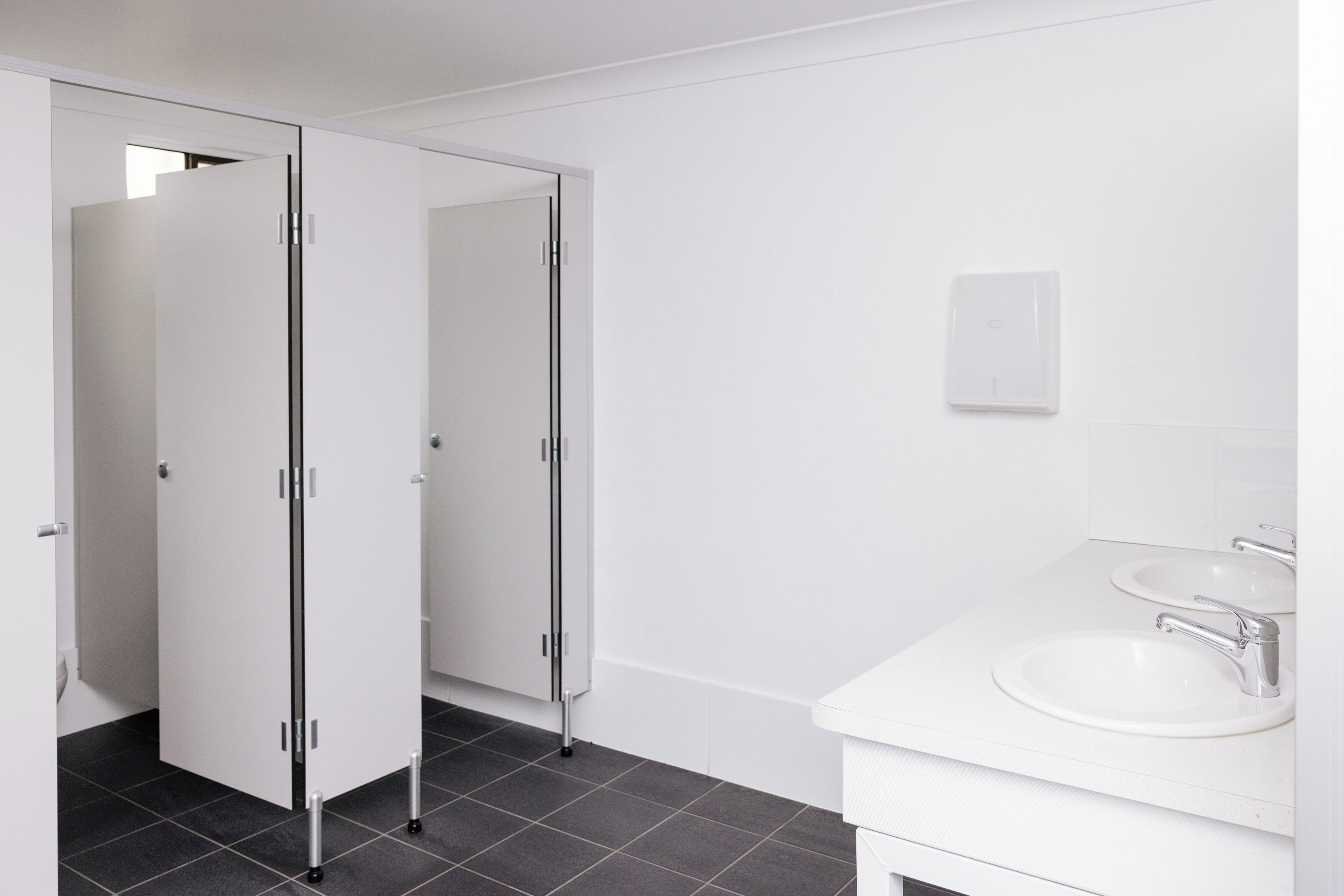 A modern bathroom with a white sink, mirror, and two glass doors leading to a shower area.