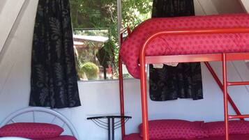 Un dormitorio con literas, una cama individual, una silla y un ventanal con cortinas.