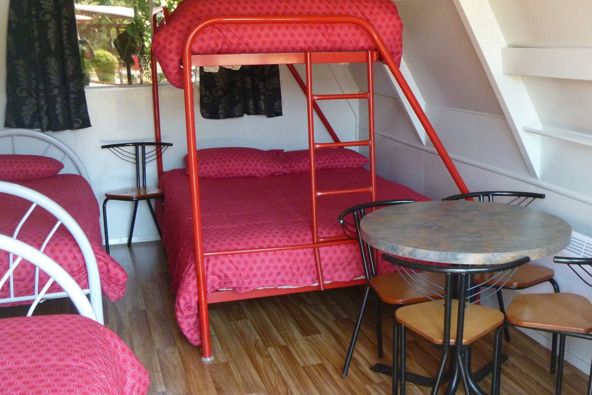 A dormitory room with bunk beds, a round table, and two chairs.