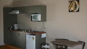 Une cuisine compacte équipée d’un four à micro-ondes, d’un petit réfrigérateur et d’une table à manger avec des chaises.