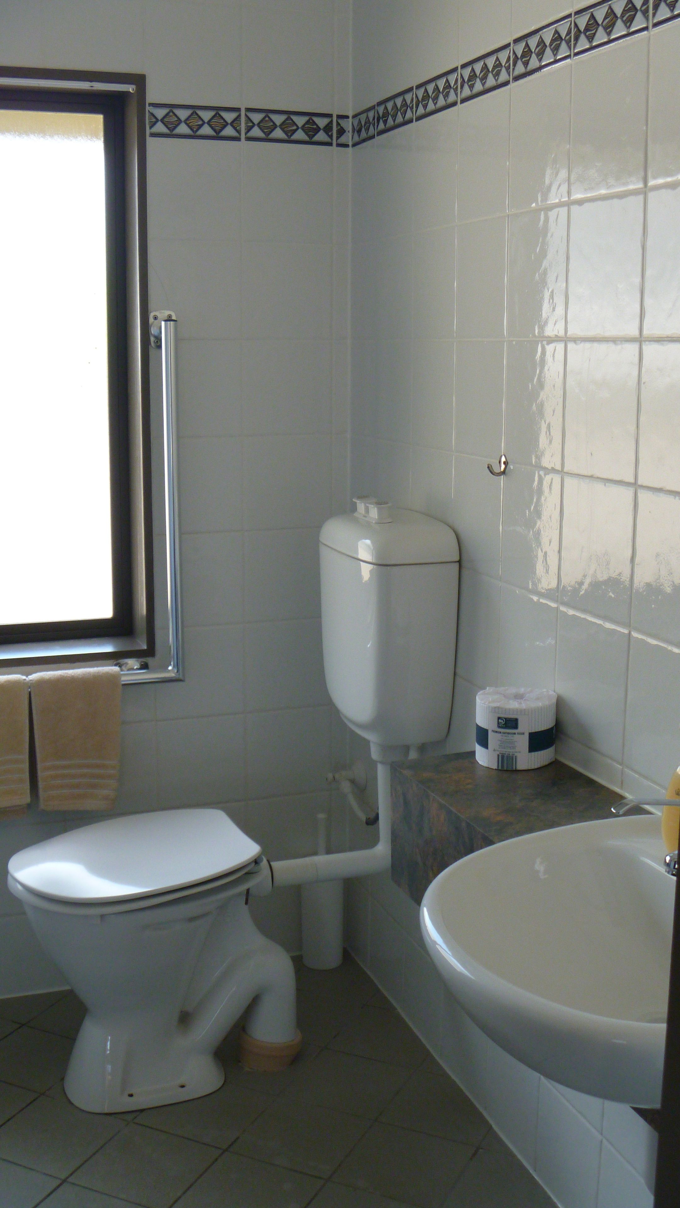 A bathroom with a toilet, sink, and window.
