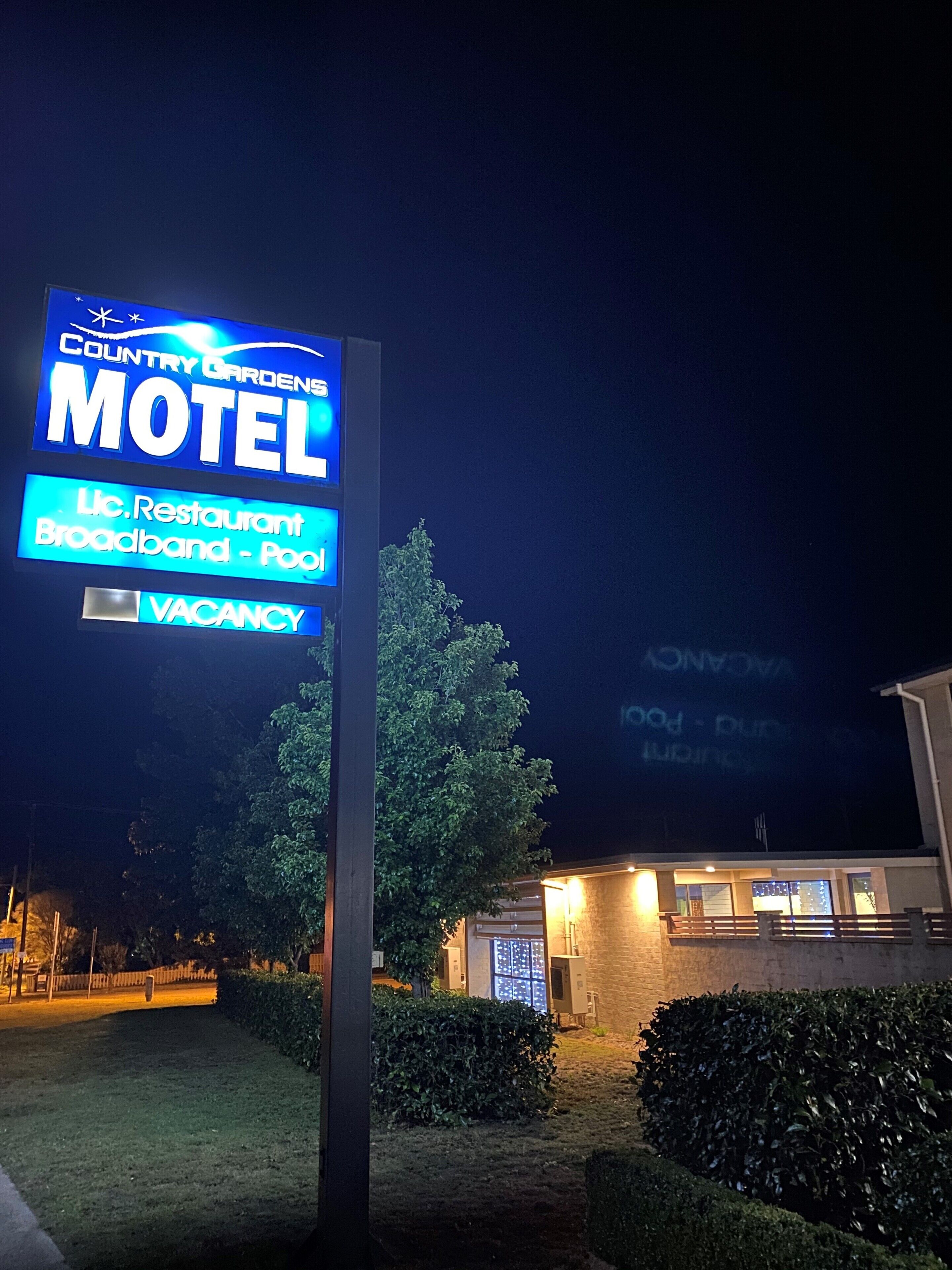 A Country Gardens Motel sign with amenities including a restaurant, broadband, and pool.