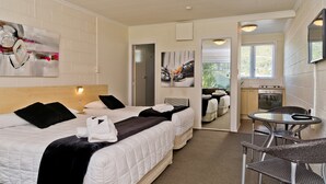 A hotel room with a large bed, a small dining table, and a kitchenette.