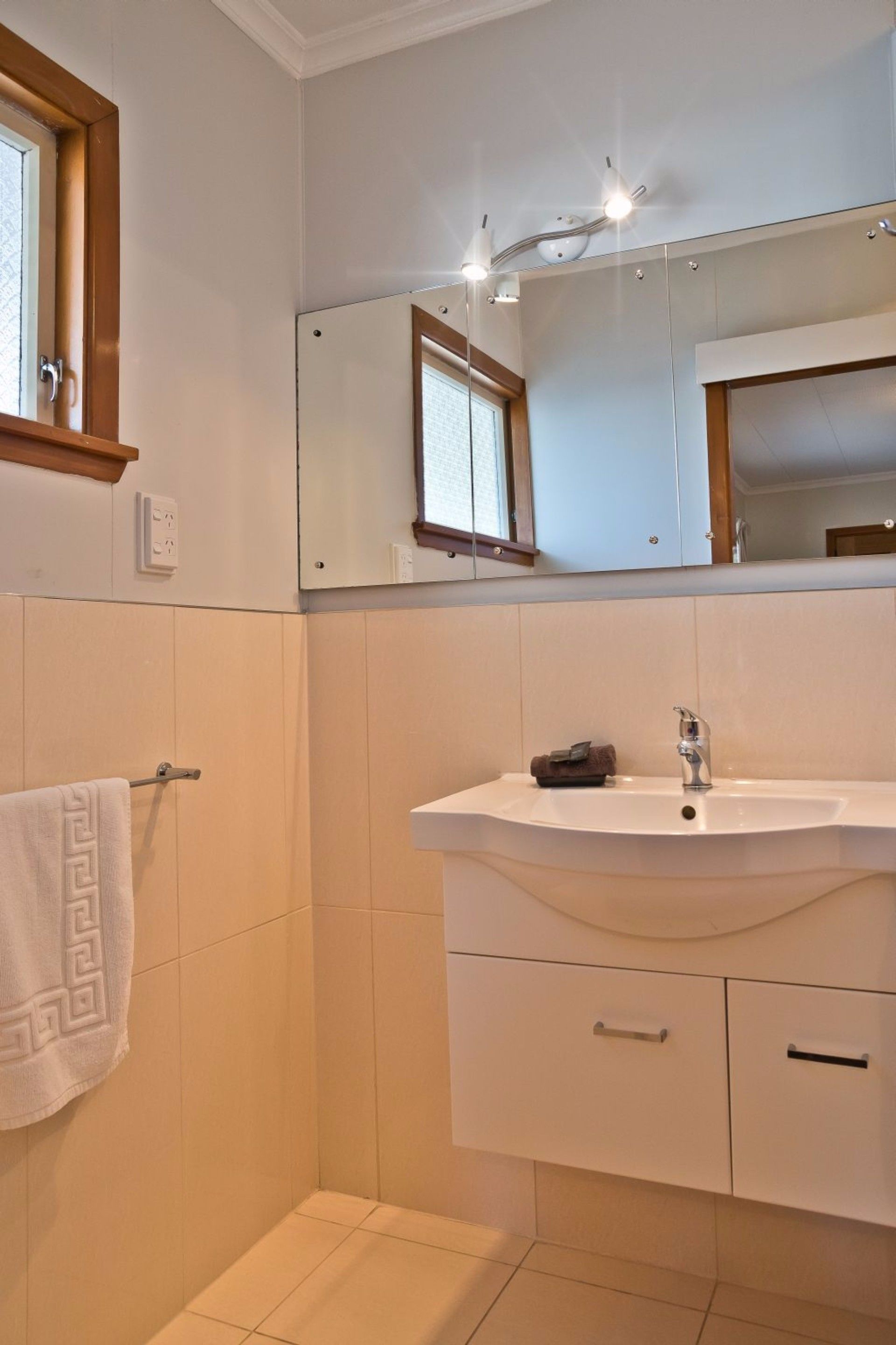 Une salle de bain avec un lavabo blanc, un miroir et un porte-serviettes.