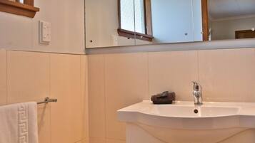 Une salle de bain avec un lavabo blanc, un miroir et un porte-serviettes.