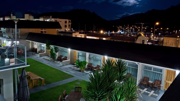 A hotel with a rooftop patio, outdoor seating, and a view of the city and mountains at night.