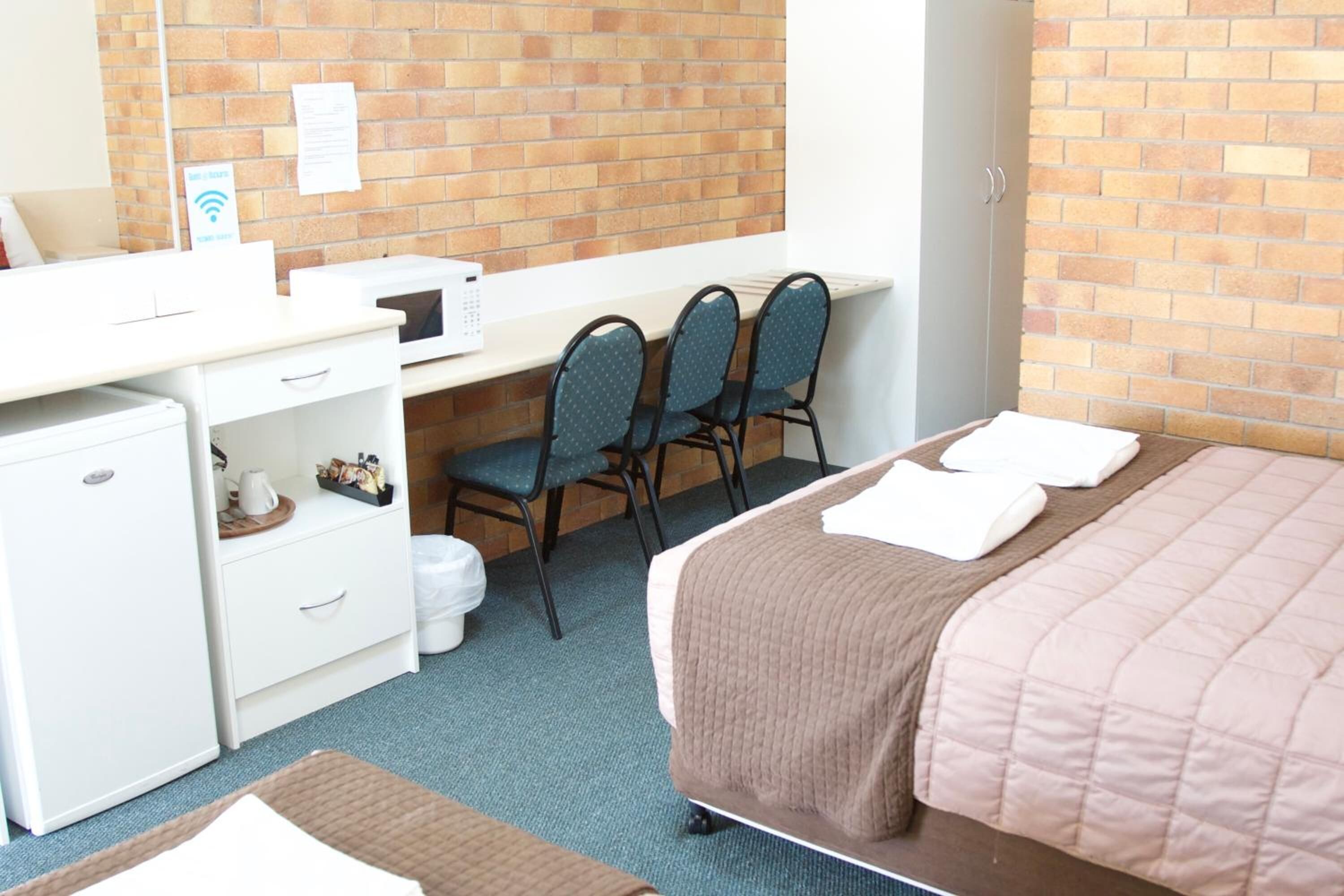 Une chambre d’hôtel équipée d’un lit, d’un bureau avec des chaises, d’un petit réfrigérateur et d’un four à micro-ondes.
