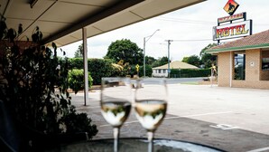 Un motel avec une enseigne, deux verres à vin vides sur une table et une vue sur la rue.