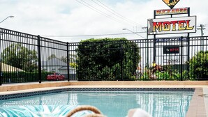 Un panier en osier près d’une piscine, avec une enseigne de motel en arrière-plan.