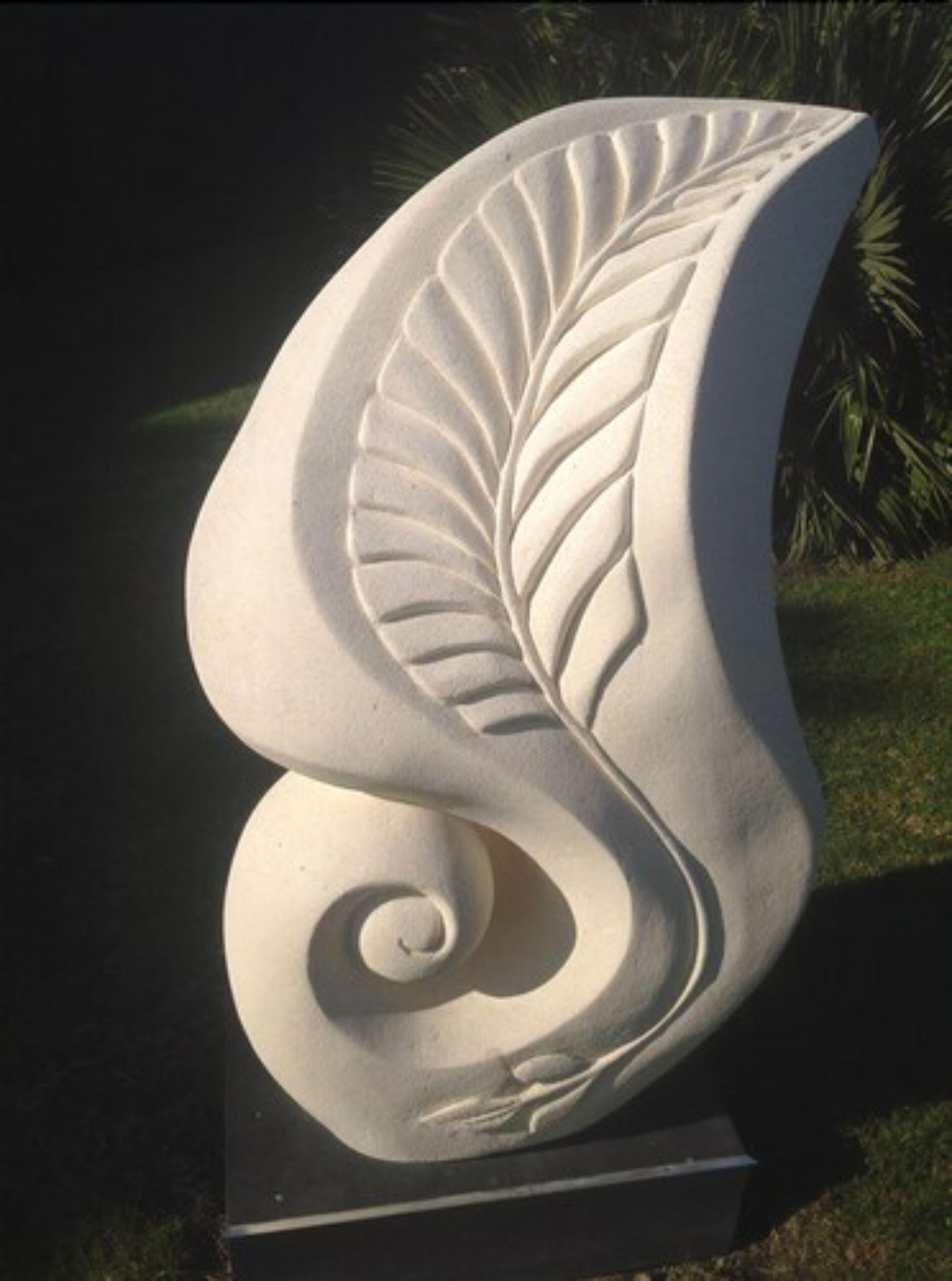 Una escultura de una hoja o pluma estilizada sobre un pedestal.