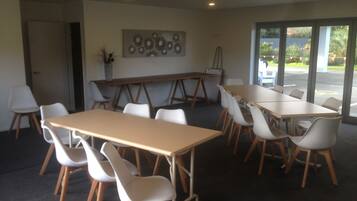 A conference room with a long table and several chairs, a painting on the wall, and a door leading outside.