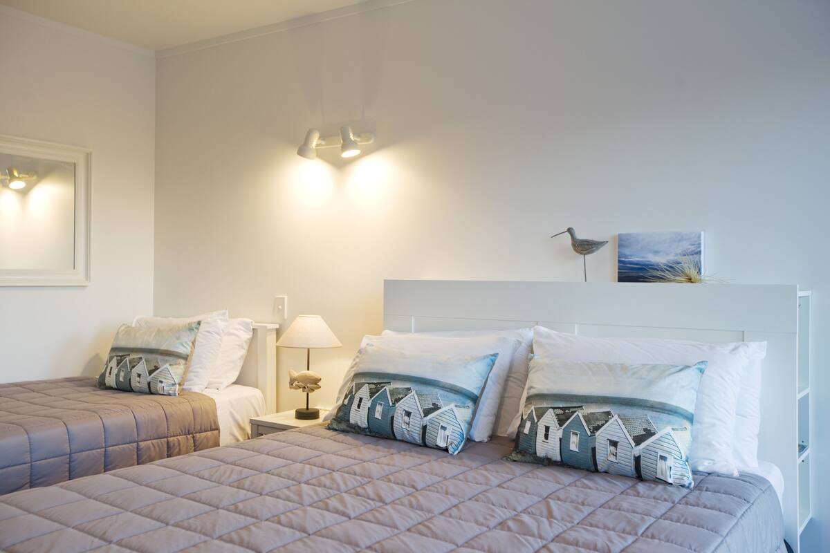 Un dormitorio con dos camas, una mesita de noche, una lámpara y decoración en la pared.