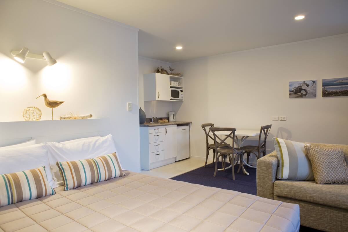 Un dormitorio moderno con una cama grande, un sofá, un comedor y una kitchenette.