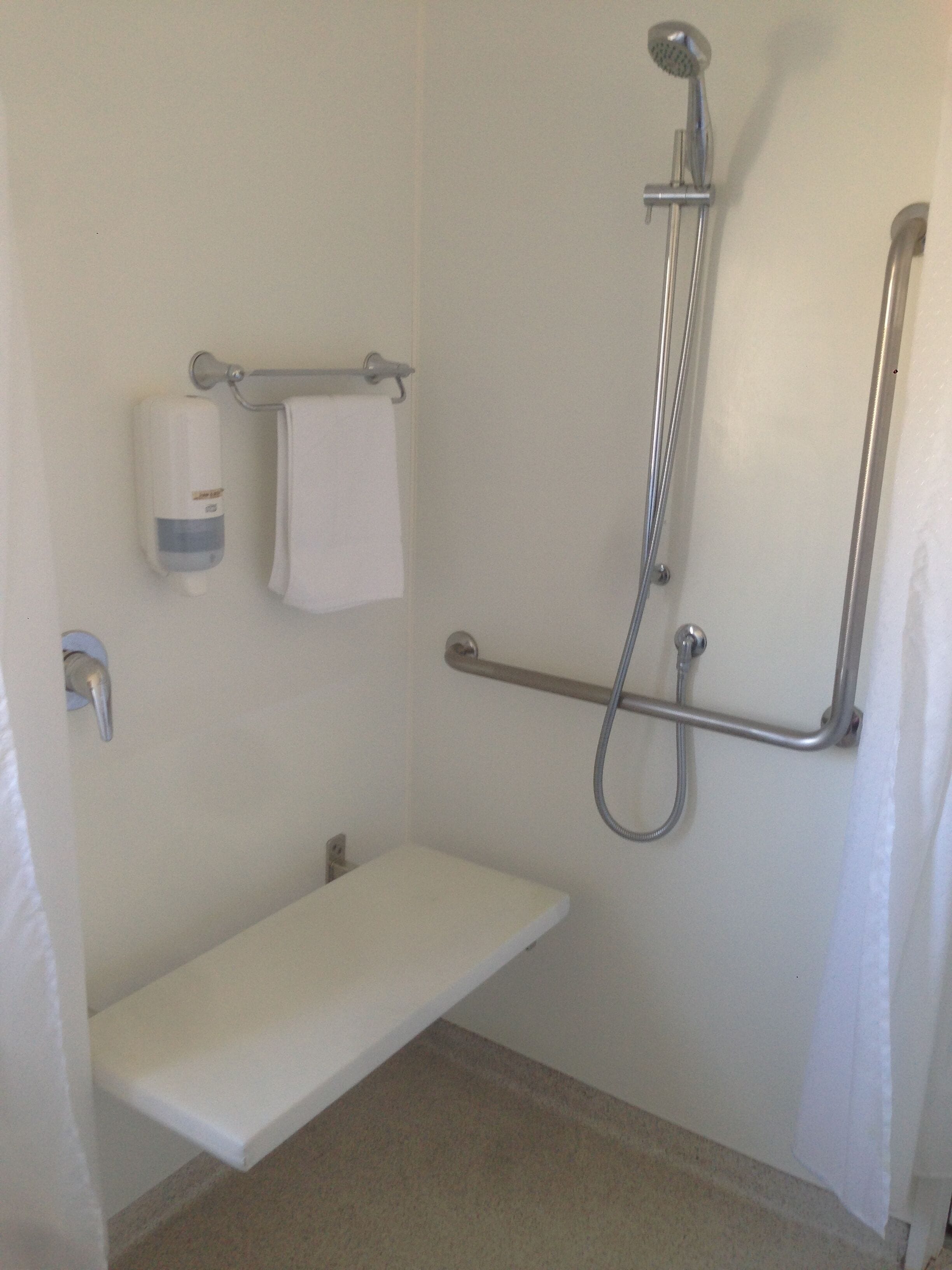 A small, white, single-person bathroom with a shower, a toilet, and a sink.