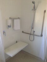 A small, white, single-person bathroom with a shower, a toilet, and a sink.