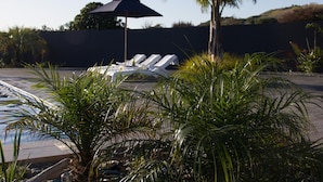 Un espace piscine avec des chaises longues et un parasol.