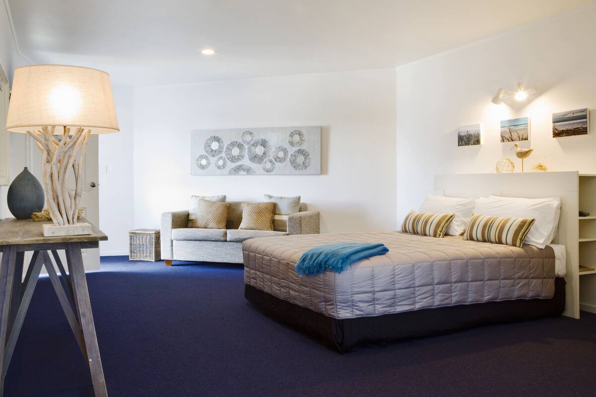 Un dormitorio con cama, sofá, lámpara y decoración en la pared.