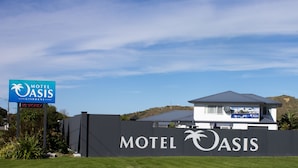 Une enseigne de motel avec un logo représentant un palmier, une pancarte indiquant « COMPLET » et un bâtiment avec une chaîne de montagnes en arrière-plan.