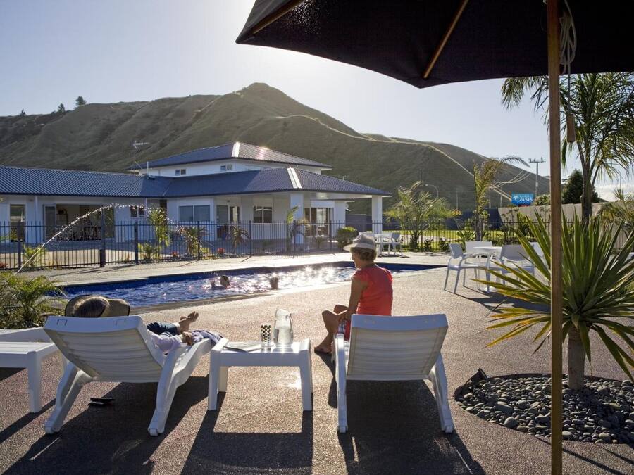 A poolside area with lounge chairs, a table with a pitcher, and a view of a mountain.