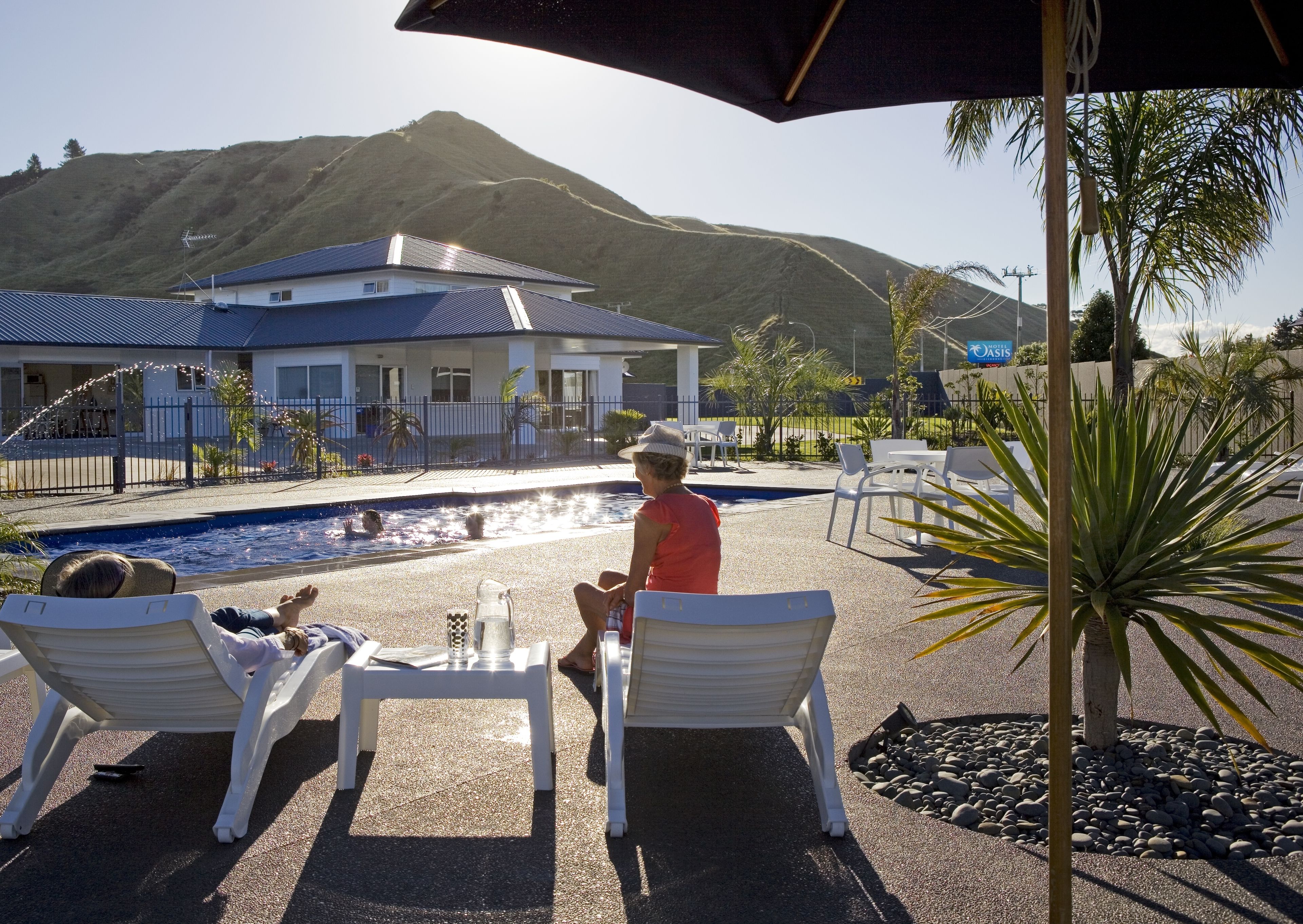 A pool area with lounge chairs, a water feature, and a mountain backdrop.