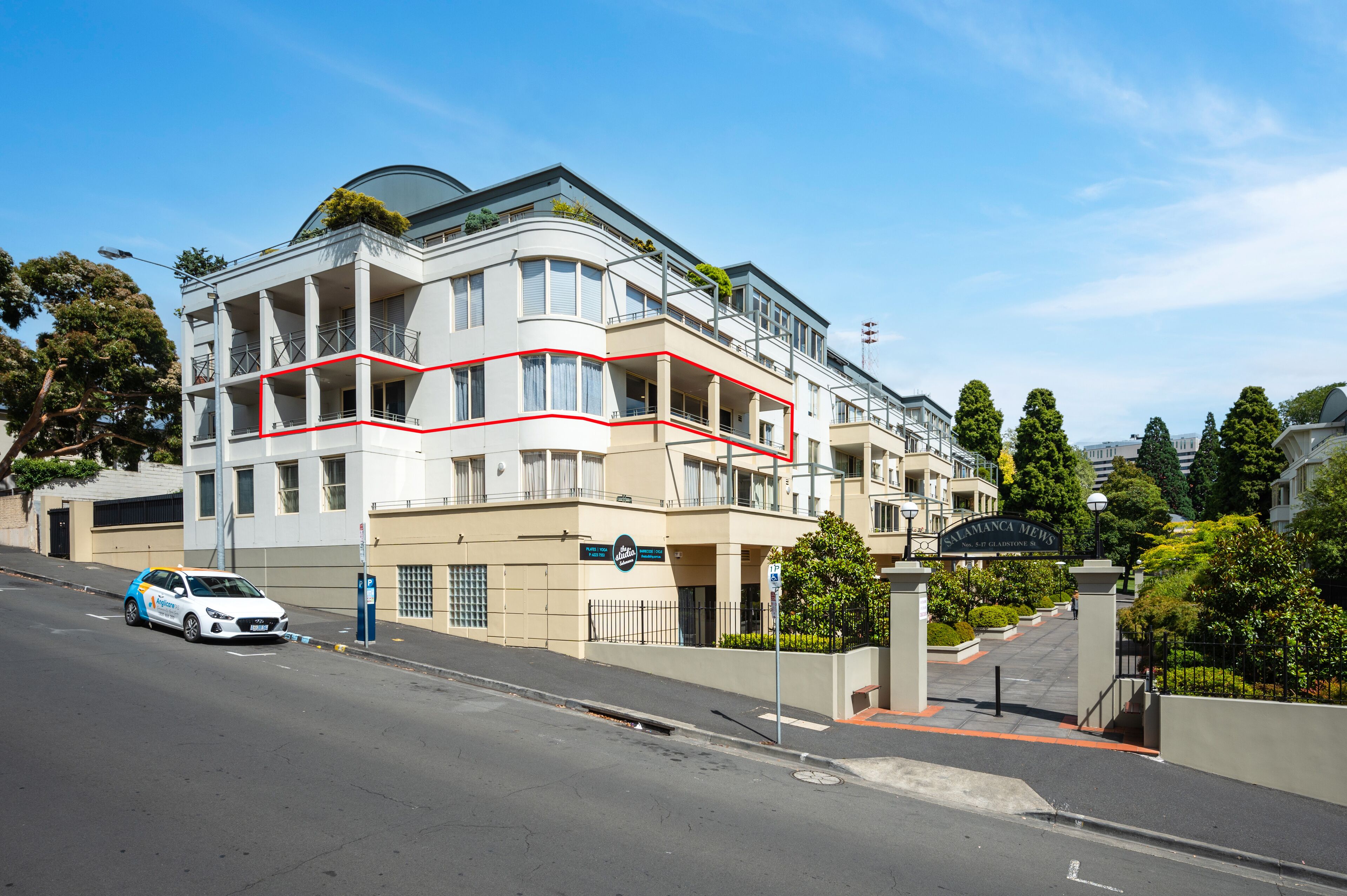 A multi-story hotel with a curved facade, balconies, and a gated entrance.