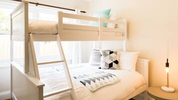 A bunk bed with a white frame and a bedside table with a lamp.