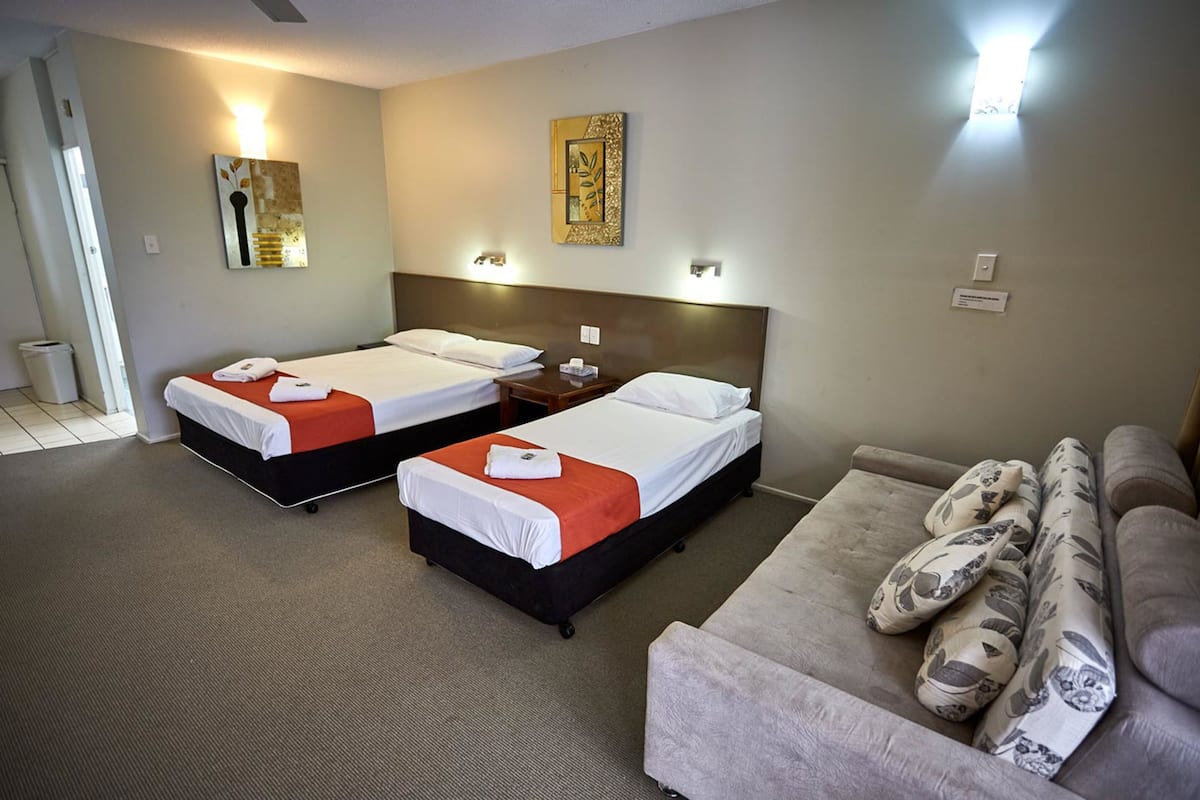 Habitación de hotel con dos camas, un sofá y una mesita.