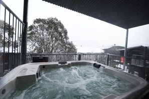 Un jacuzzi con vistas a un paisaje nevado y un edificio al fondo.