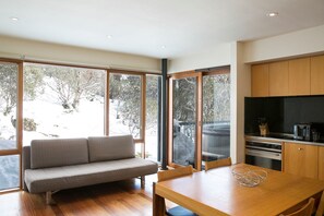 Una cocina moderna con armarios de madera, horno empotrado y comedor con mesa y sillas de madera.