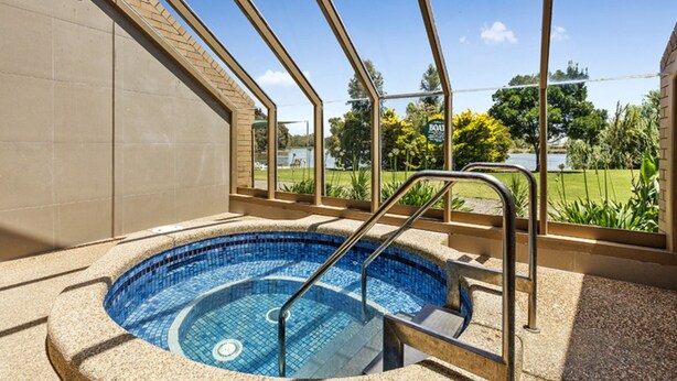 A hot tub with a view of a garden and a building in the background. - Lakeside Country Club - Numurkah (Numurkah)